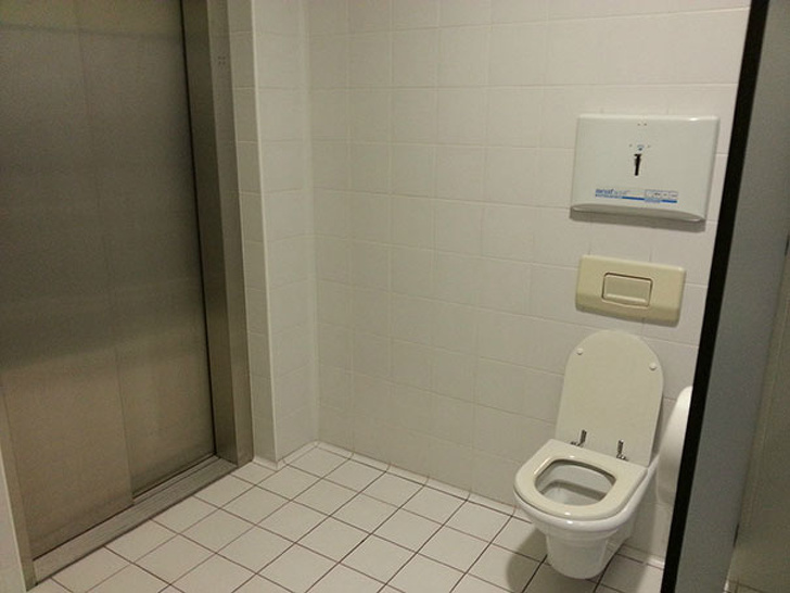 This toilet stall has an elevator inside of it.