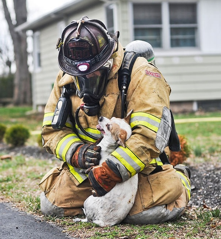 A firefighter comforting a dog rescued from a house fire