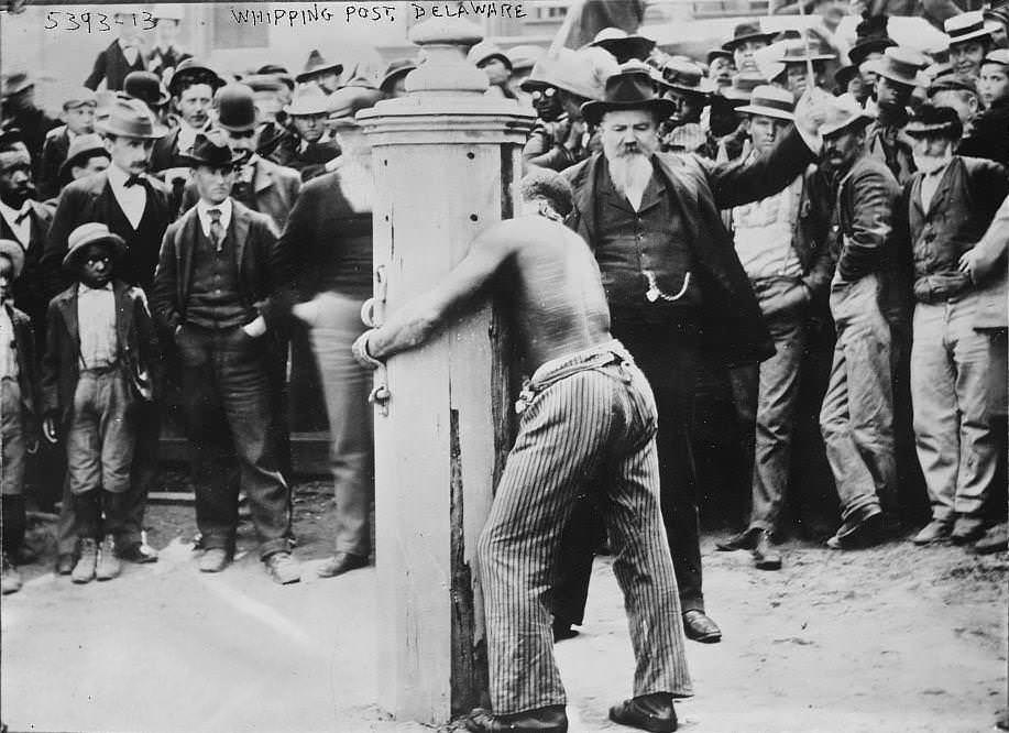 A black man is punished for a crime by being tied to a whipping post and publicly flogged in Delaware, US in 1900. Such a punishment was only for black people. 

Note: The term "cracker" was given to white people who were quick to whip their slaves. It is because the whip made a cracking sound when hitting flesh.