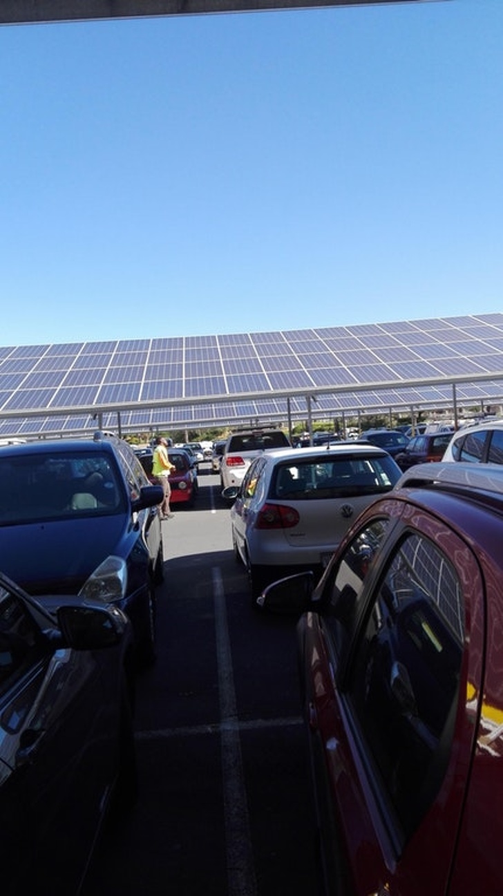 Solar panels provide shade in a parking lot.