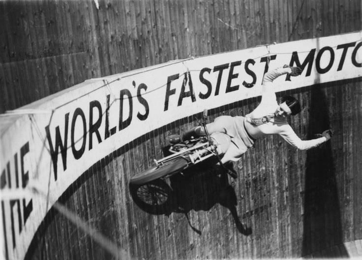 Doris Smith riding her motorcycle around the "Wall of Death" with no safety equipment and no hands at a fair in Essex, England in 1938.