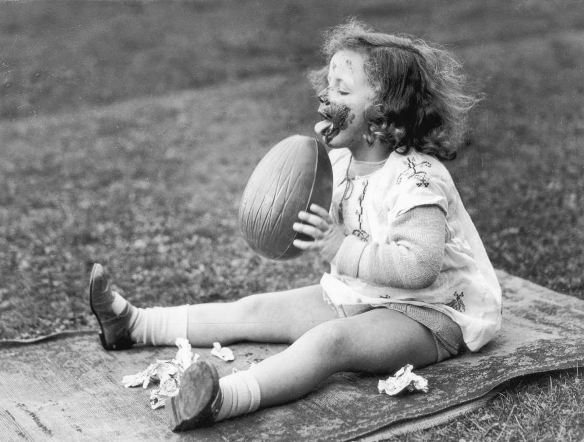 A kid eating a giant chocolate Easter egg in the US in 1930.