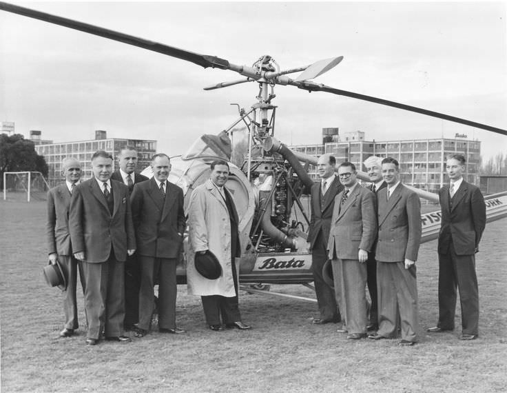 Men pose in front of a helicopter in East Tilbury, England in 1955.