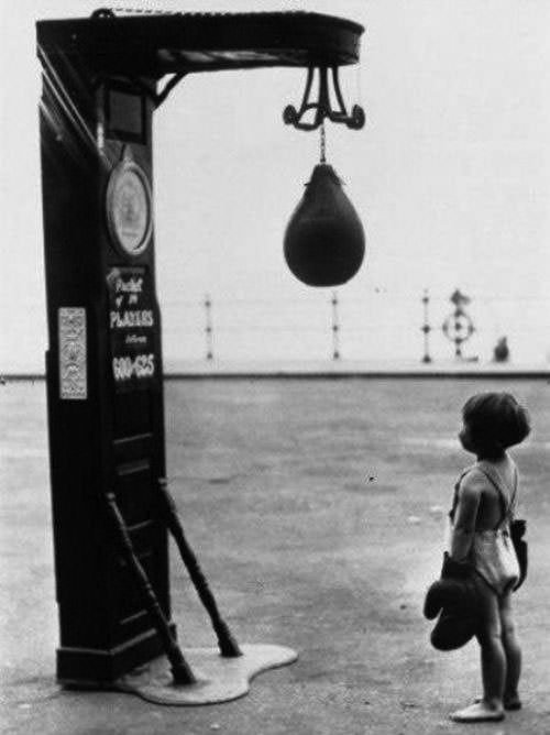 A child with boxing gloves looks at a punching bag in the US in 1937.