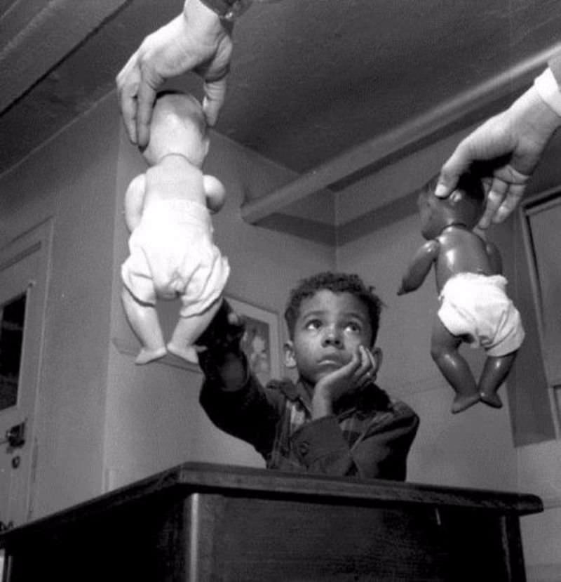 A black child picks the white doll after being asked which doll he prefers during the "Doll Test" given by married Doctors Kenneth and Mamie Clark in the 1940s to test the effects of segregation on children in the US. The same child also picked the white doll when asked to pick “the doll that you like to play with,” “the doll that is a nice doll,” and “the doll that is a nice color”.