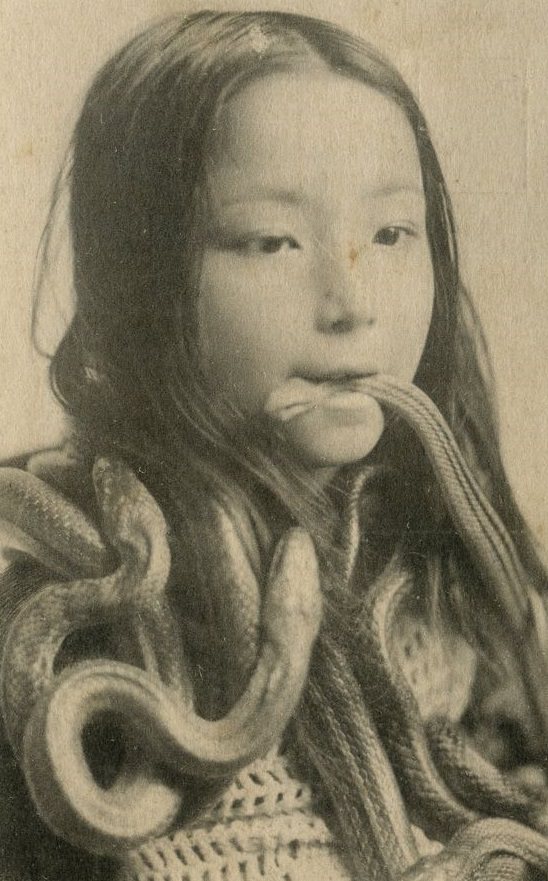 A young girl from Japan with live snakes all on her and in her mouth in 1928.
