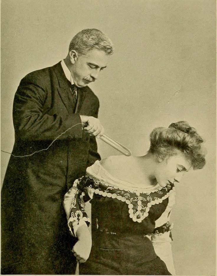 A man demonstrates a device that gives electric currents to stimulate muscles in the US in 1907.