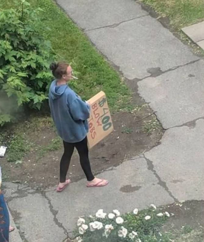 woman walking around with sign that says blowjobs for $4