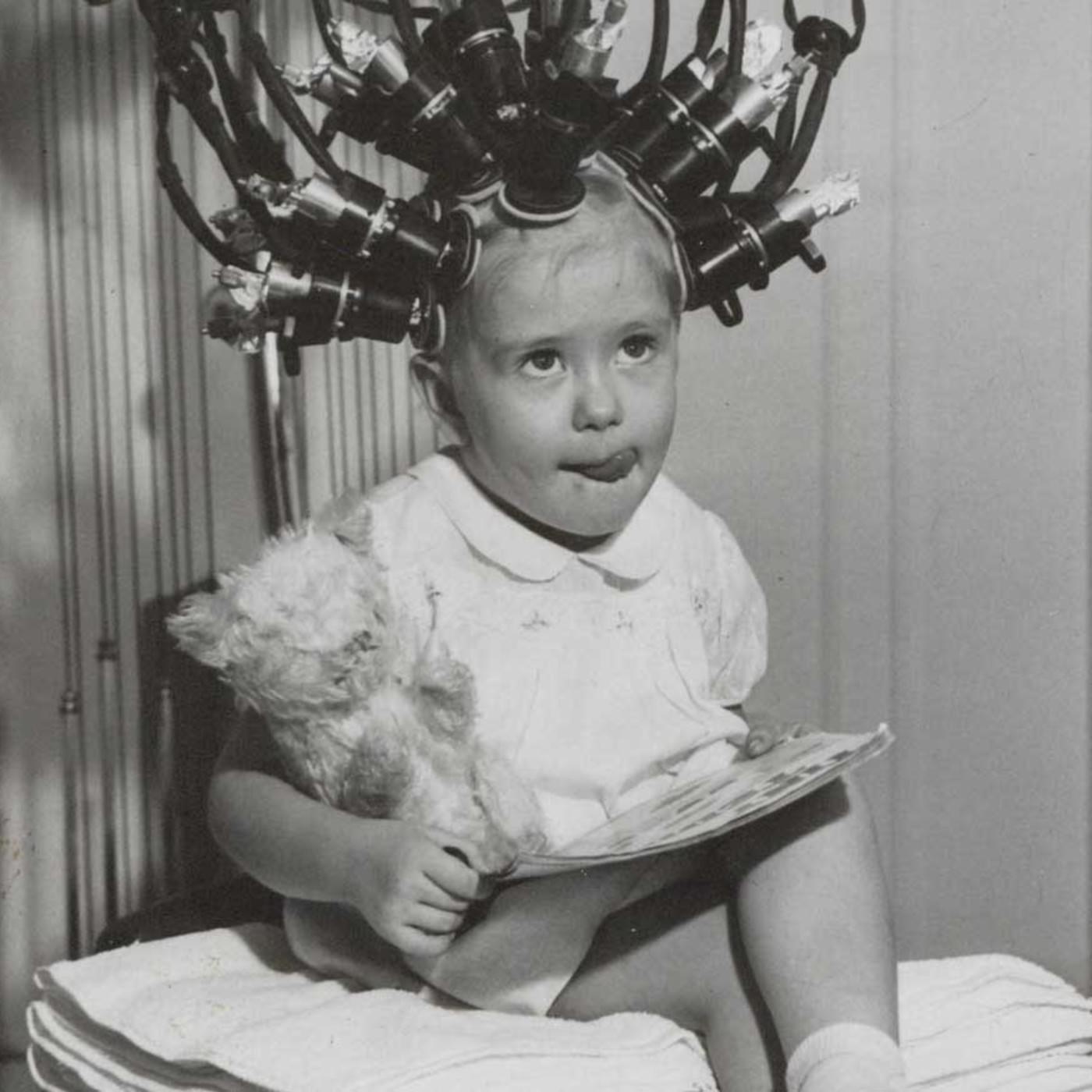 A young girl getting her hair curled, marketed as a permanent procedure, to look like Shirley Temple in Berlin, Germany in 1938.