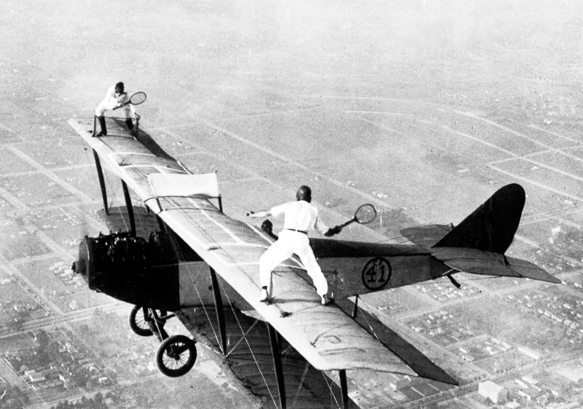 2 Stuntmen known as wing walkers pretend to play tennis on a plane in 1923.