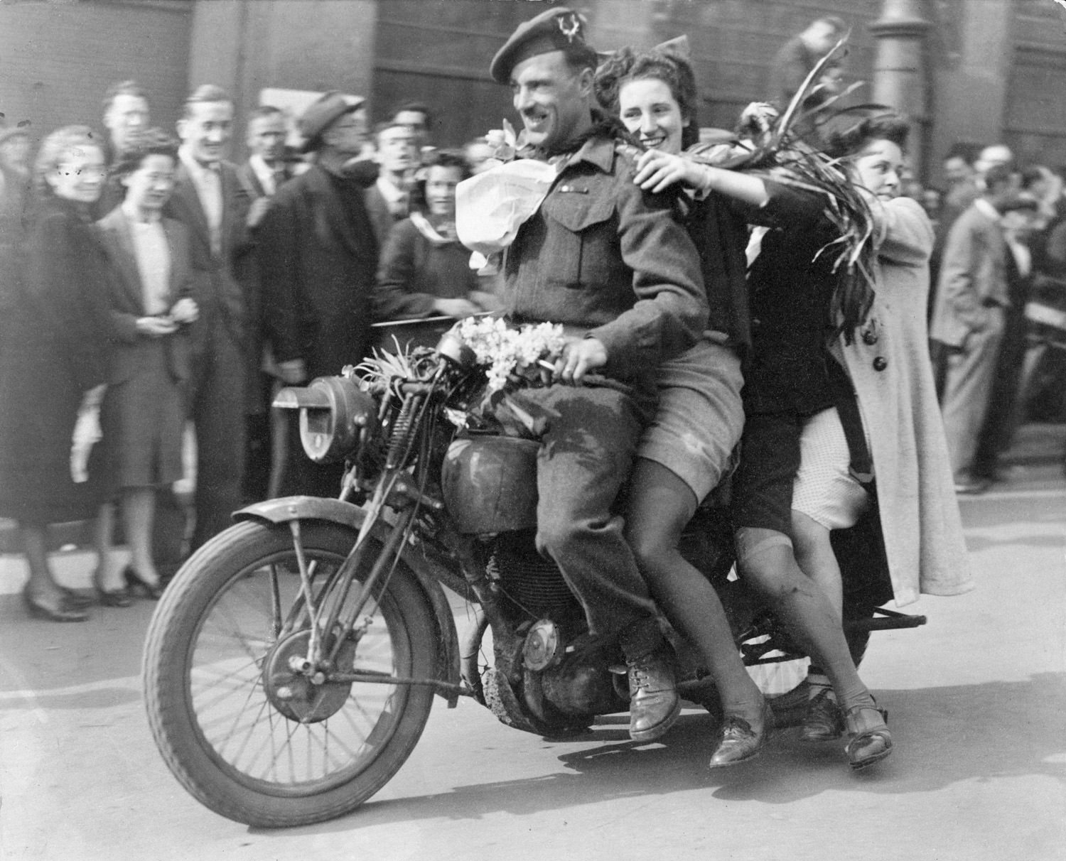 A Canadian soldier rides a motorcycle with 3 happy ladies in Amsterdam, The Netherlands in 1945.