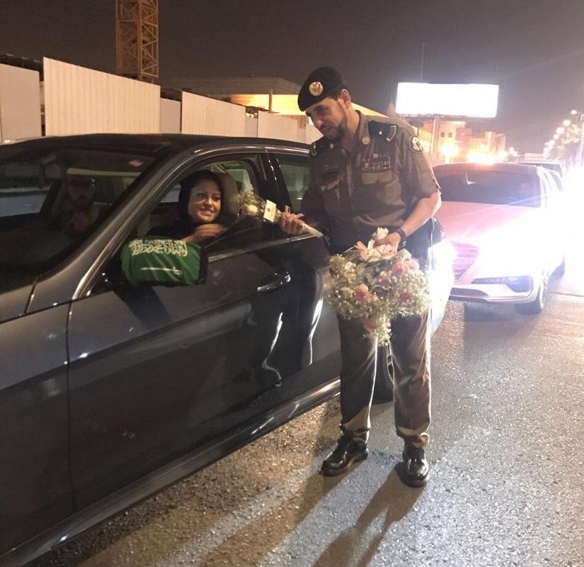 Saudi police officers hand out roses to female drivers. (Today is the first-day women can legally drive in Saudi Arabia)