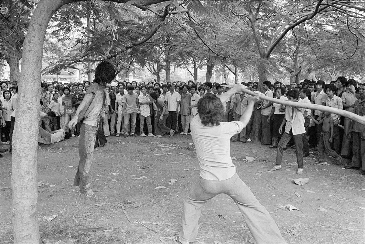 A man beats a murdered student strung up like a pinata during the Thammasat University massacre in Bangkok, Thailand in 1976.