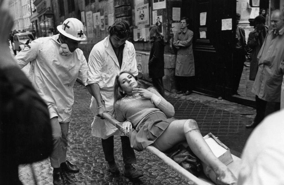 An injured student looking tough as hell despite having bruises and cuts on her legs preventing her from walking after clashes with police during the Student Uprising in France in 1968.