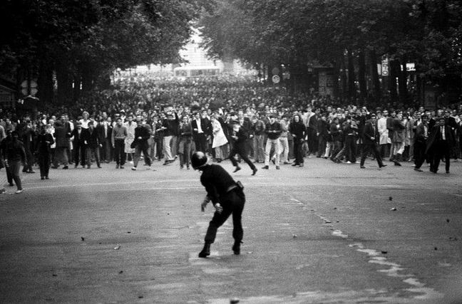 Continuing from the previous picture, here is an officer ahead of his unit throwing a gas grenade towards thousands of protesters during the Student Uprising in France in 1968.