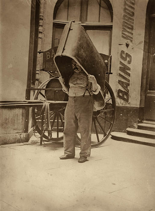 What appears to be an unhappy man carrying a bath tub in Paris, France in 1900.