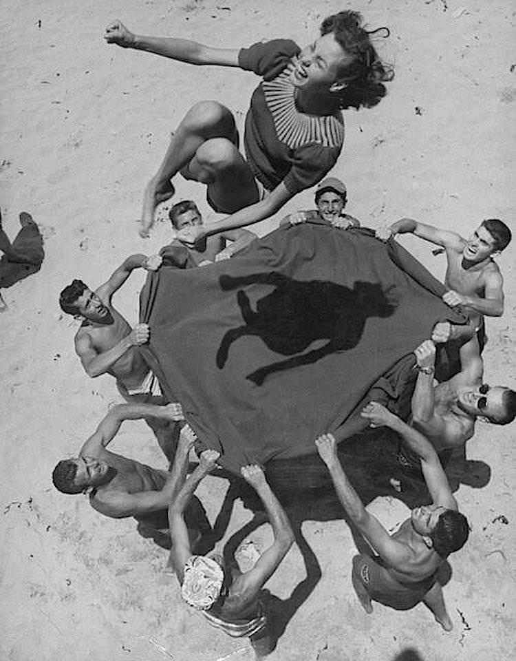 A woman on the beach getting tossed up casting an odd shadow in the US in 1958.