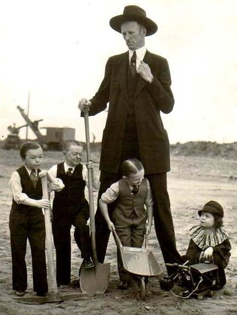 A very tall man poses with very short dwarfs for Ringling Bros Barnum Bailey Circus Sideshow in the US in 1908.