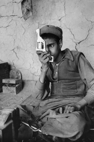 A boy looks at a counterfeit gun his shop made in Afghanistan in 1955.