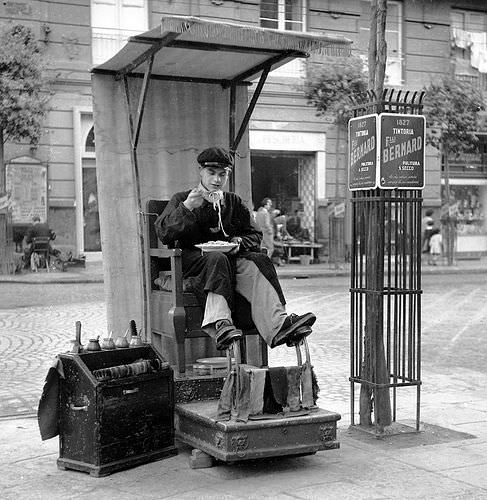 A shoe shiner takes his break to eat pasta in Naples, Italy in 1950.