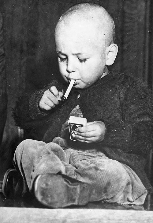 A 2 year old lighting a cigarette in Los Angeles, CA, US in 1927.