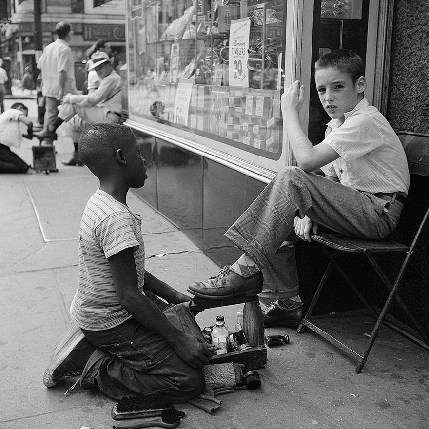 A young boy shines the shoes of another boy in NYC, US in 1955.