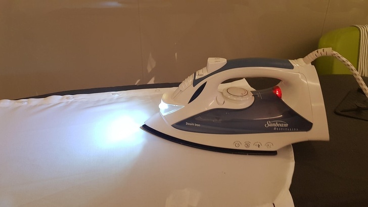 This hotel iron has a light on it to help you see the wrinkles as you iron.