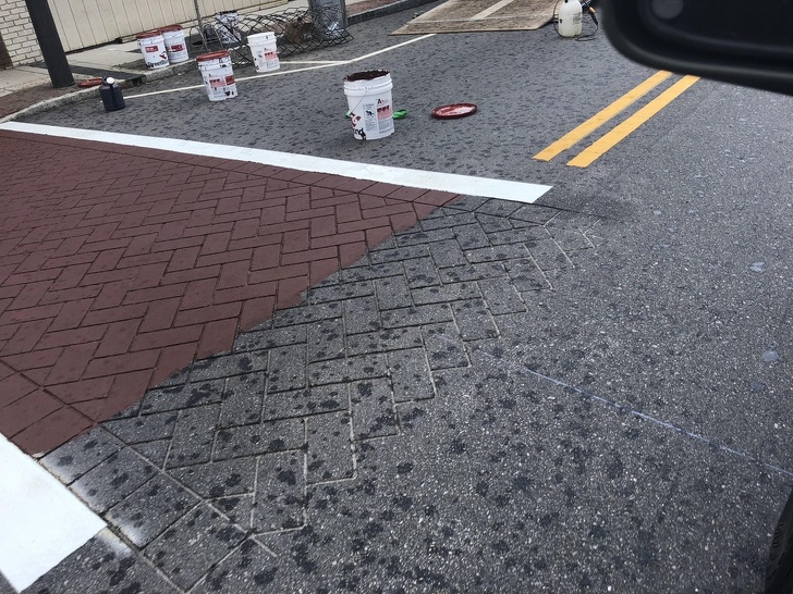 They are cutting shapes into the concrete and painting it to make it look like the sidewalk was made of bricks.