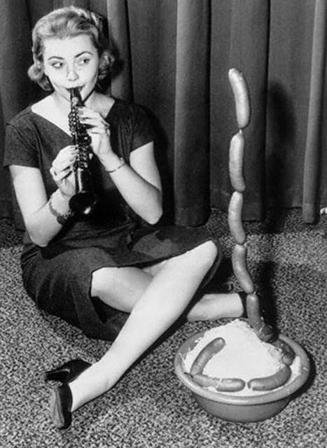 A model pretending to be a snake charmer with hot dogs for a promotion in the US in 1956.