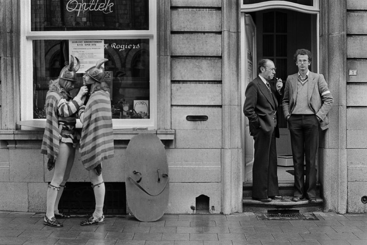 Performers prepare their costumes next to citizens in Ypres, Belgium, in 1975.