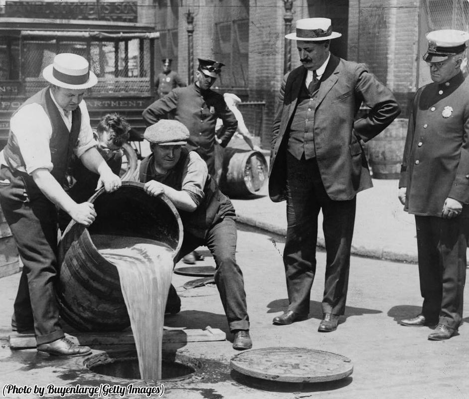 New York agents pour booze into sewer following a raid during the height of prohibition, circa 1921.