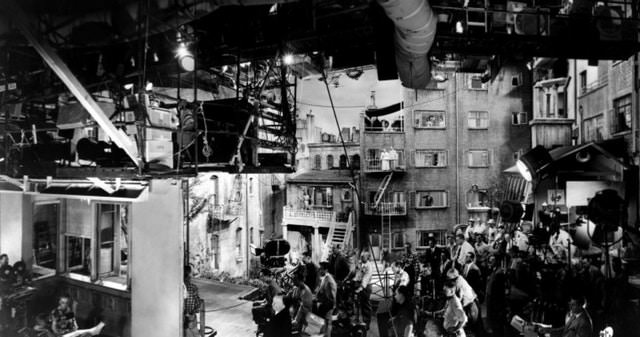 A backstage shot of the set of Hitchock's Rear Window, 1954. The full set consisted of 31 apartments, 8 of which were completely furnished, with 1000 arc lights to simulate sunlight. This picture shows a populated BTS shot, but the one below gives an excellent view in a bit of a different perspective, and in color.