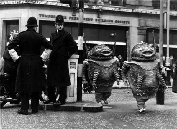 2 Officers watch alien characters for a film get into position in London, England in 1965.