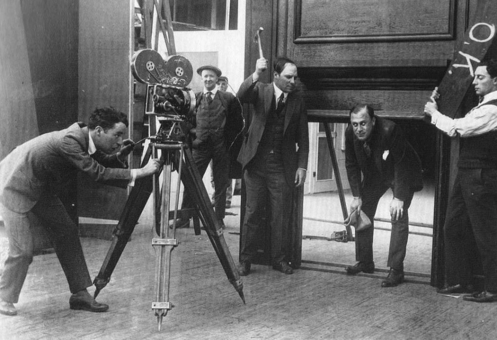 Charlie Chaplin (left) visiting the set of an unknown Buster Keaton (right) film with a bunch of executives like H. M. Horkheimer (crouching) and Lou Anger (with hammer) who managed Fatty Arbuckle (1918 or 1919).