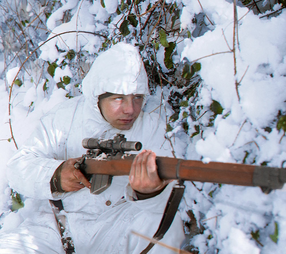 A 1st Royal Ulster Rifles, 6th Airborne Division (UK) sniper, on patrol in the Ardennes, wearing a snow camouflage suit. 14 January 1945.
