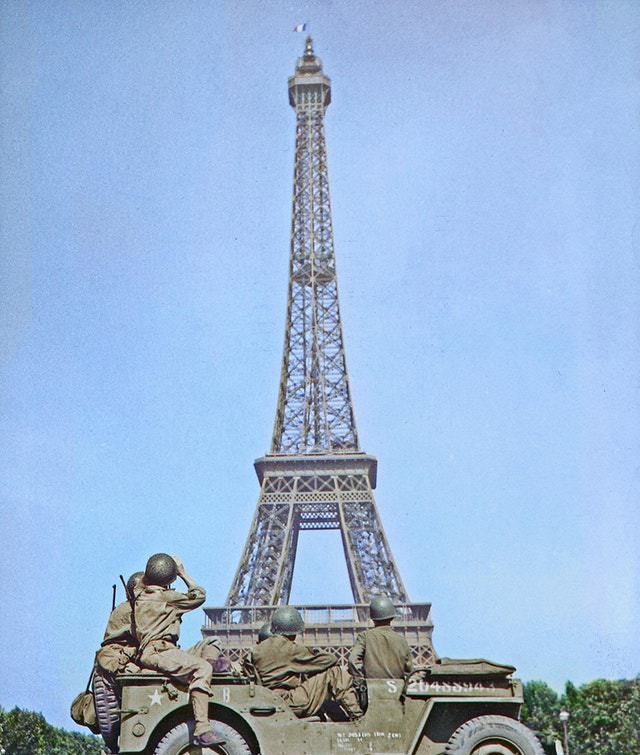 American soldiers watch as the Tricolor flies from the Eiffel Tower again, c. 25 August 1944.