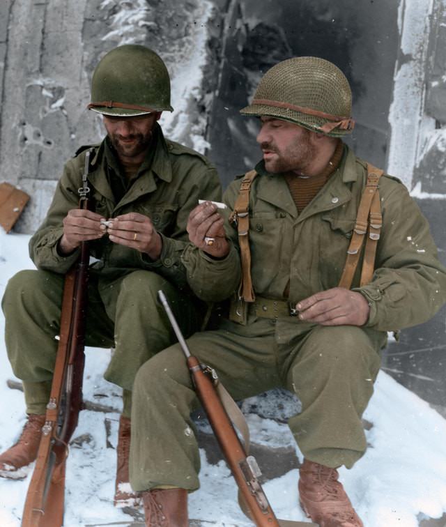 Two riflemen from the 317th Infantry Regiment, 80th Infantry Division, take a moment to roll their own cigarettes in Goesdorf after 27 days of fighting. January 10, 1945.