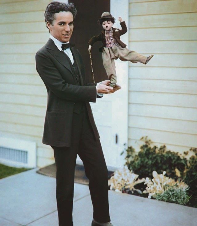Charlie Chaplin holding a puppet version of his character "The Tramp", ca. 1914.