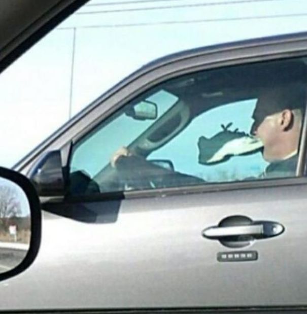 guy driving with shoe in mouth