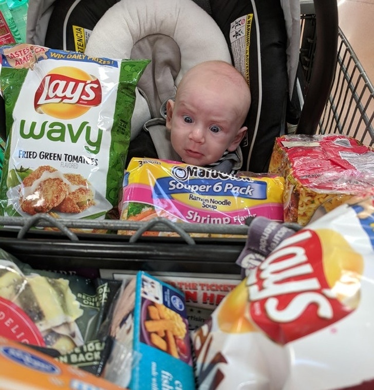 An infant waking up from a nap finds himself covered in groceries