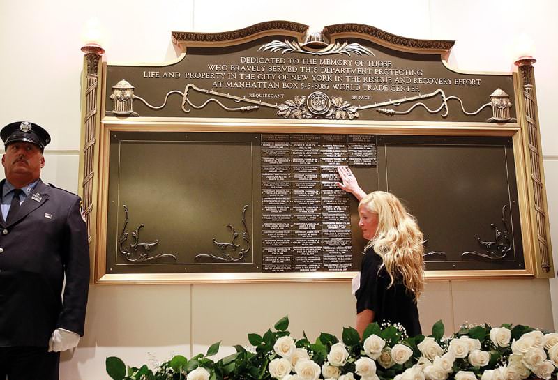 FDNY Memorial Wall at the FDNY Headquarters in Brooklyn, New York.

A woman touches a name on a plaque in honor of FDNY firefighters who have died from illness related to working at ground zero.