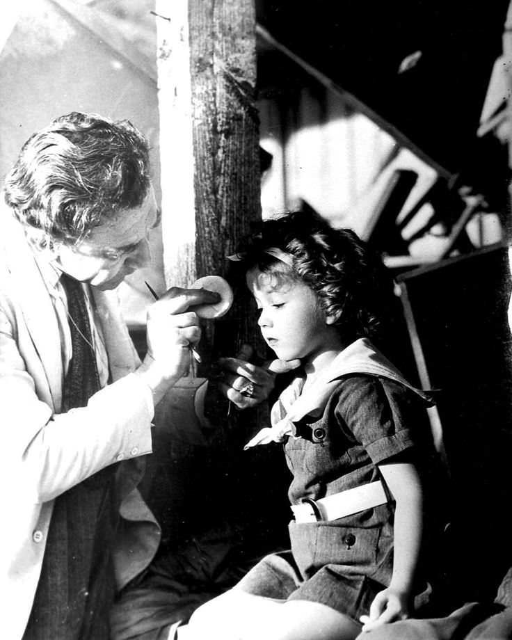 6 Year old Shirley Temple getting her makeup applied prior to a scene in Stand Up and Cheer! (1934).