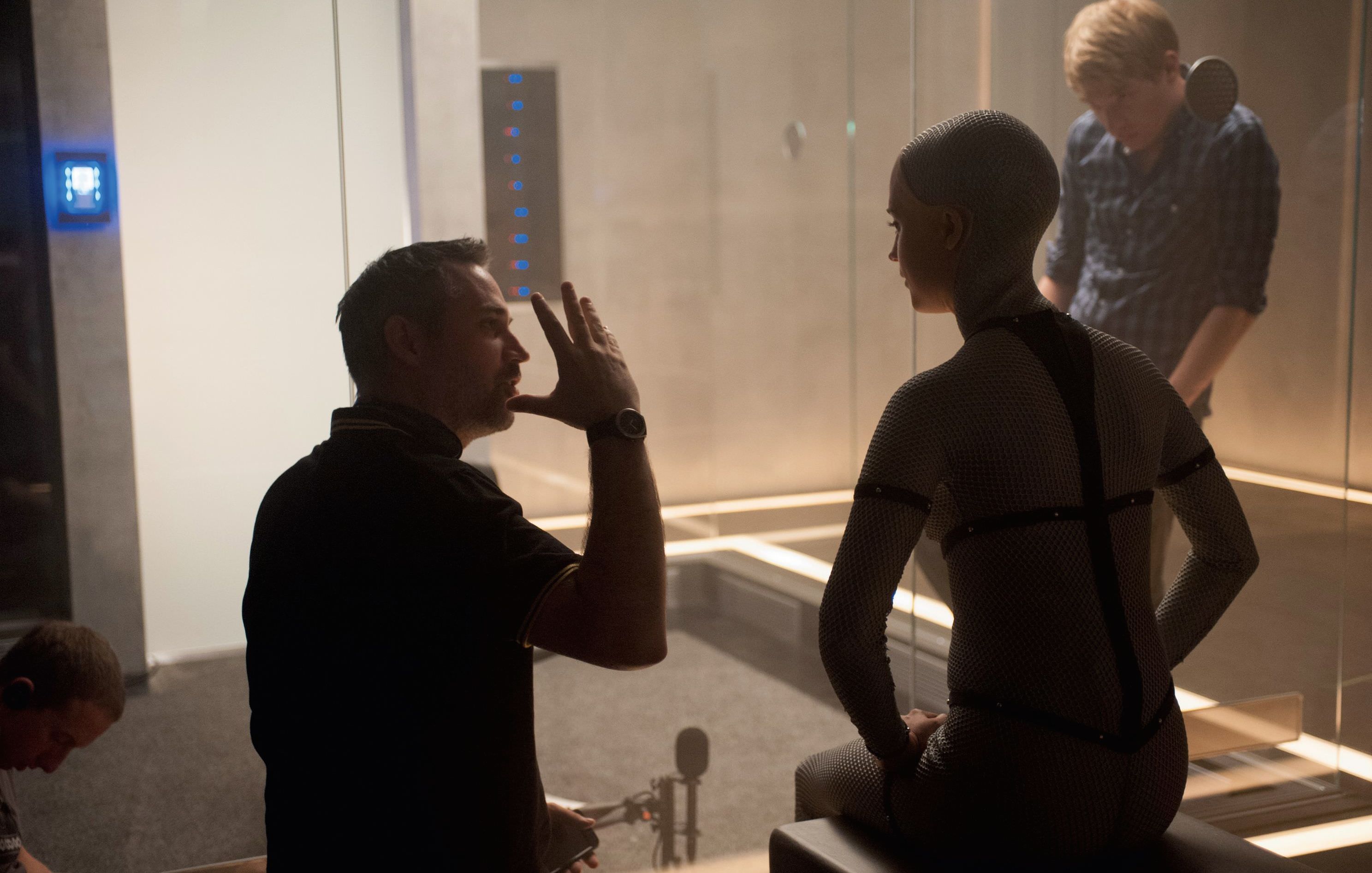 Director Alex Garland prepares Alicia Vikander and Domhnall Gleeson for a scene in Ex Machina (2014).