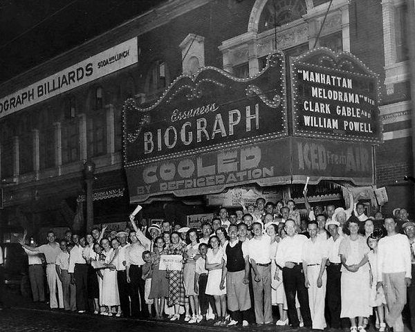Crowd of people celebrating and posing for a photo moments after notorious gangster John Dillinger was shot dead on the sidewalk.
