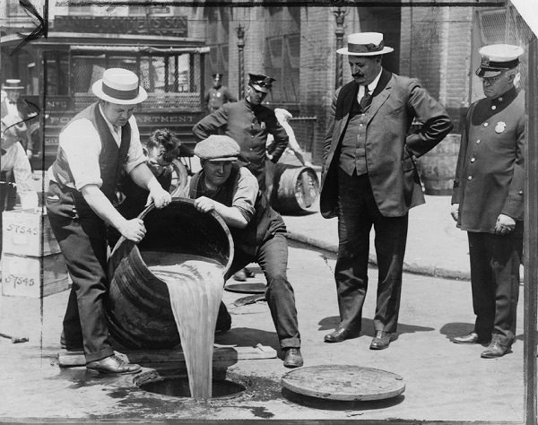 Police empty a barrel of beer into the sewer during prohibition,