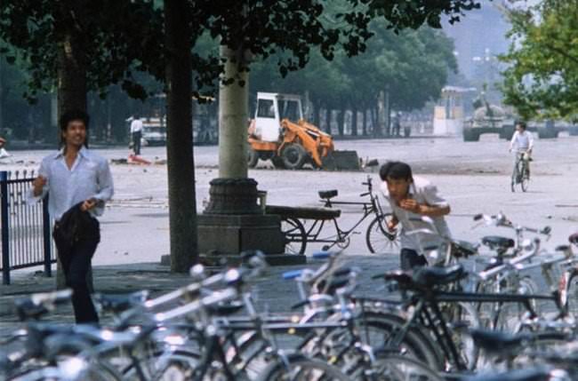 A different angle of Tiananmen Square's "Tank Man" standoff. "Tank Man" is on the left side of the bulldozer, between the two trees behind the running man. You can see the tanks behind the cyclist in the right background.