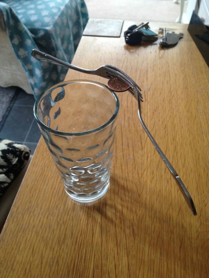 Two forks held by a penny on a glass