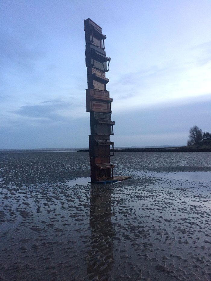 Pianos stacked on a beach