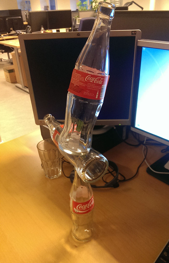 Glass Coke bottles balancing on desk