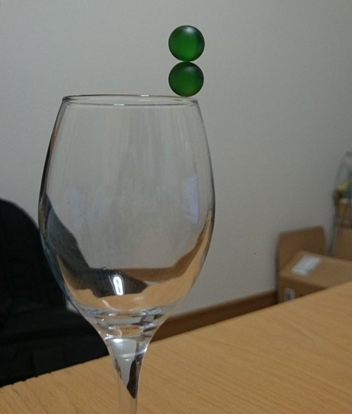 Marbles balanced on brim of wine glass